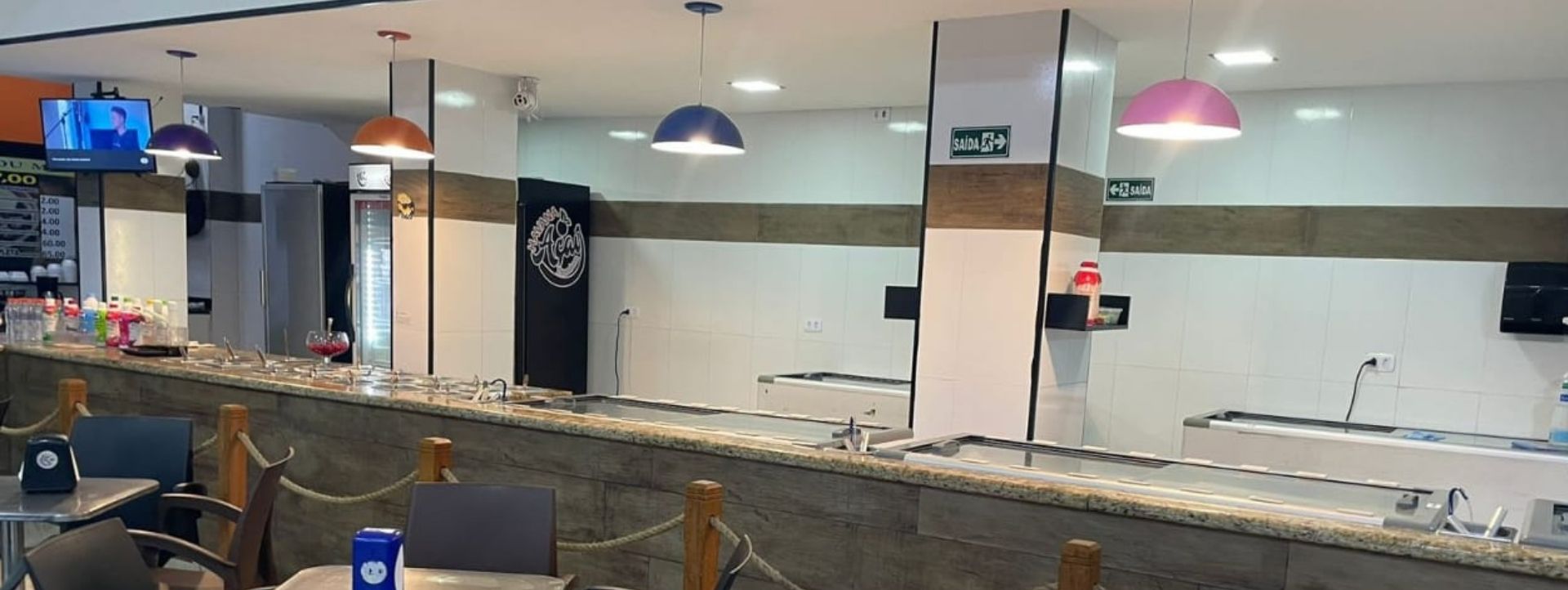 Área interna com mesas, cadeiras e o balcão de atendimento.